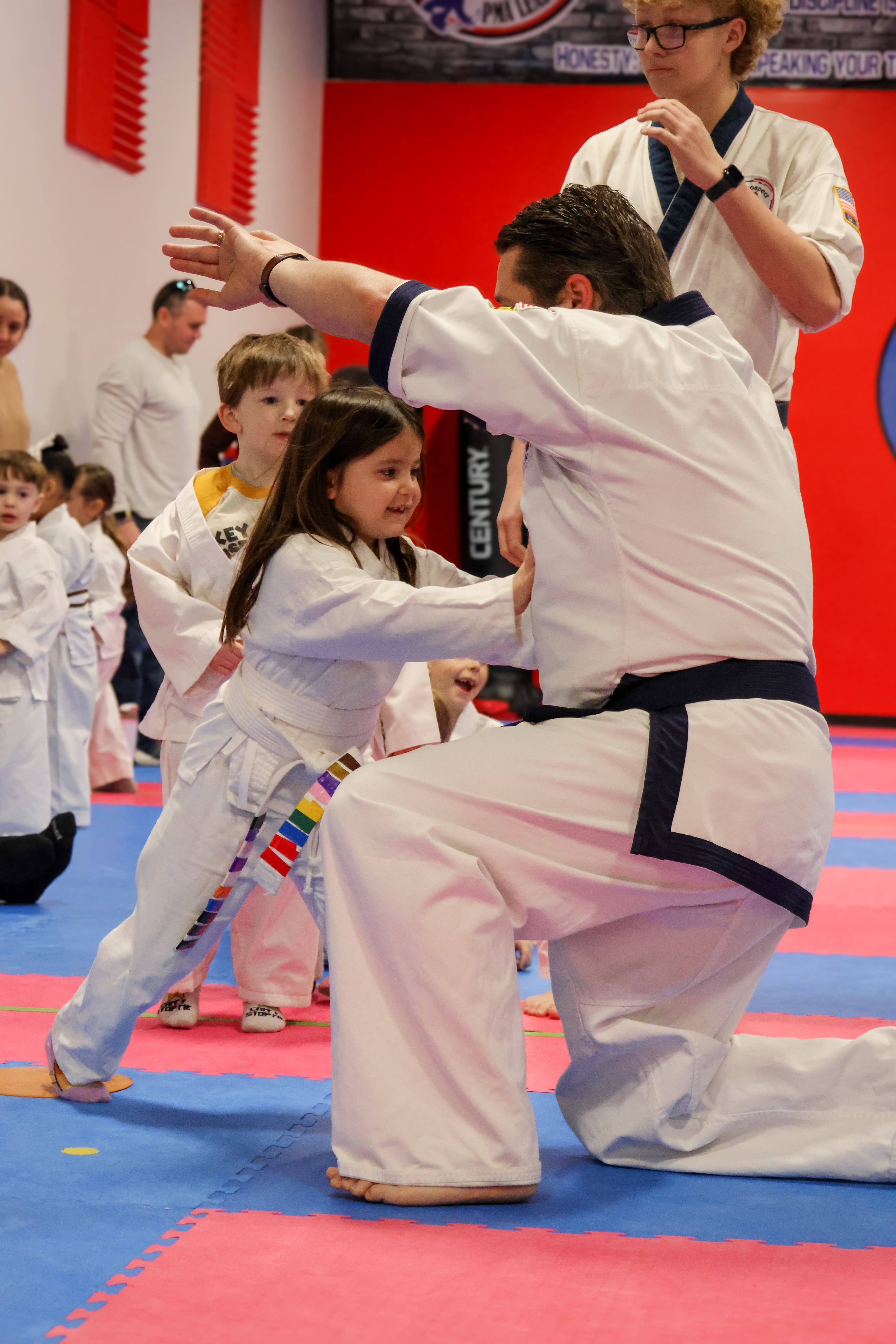 Instructor teaching self-defense technique to young students